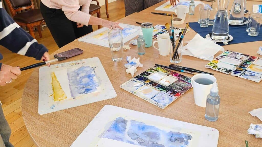 Workshop table with watercolor paintings in progress, surrounded by a group of people enjoying a guided art experience in Bristol — Afternoon Tea Bristol, What’s On Bristol, Art Workshop.